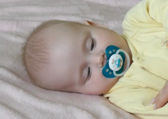 Baby using blue pacifer to sleep